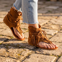 Camel suede fringed hippie sandals worn on Mediterranean cobblestones