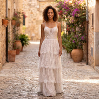 Ruffled boho lace wedding dress worn by a smiling model outdoors