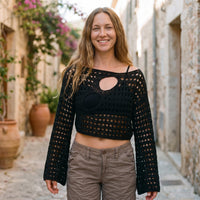 Lächelndes Model im schwarzen durchsichtigen Häkel-Crop-Top