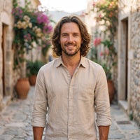 Smiling model wearing the ecru linen men's hippie shirt in an alley