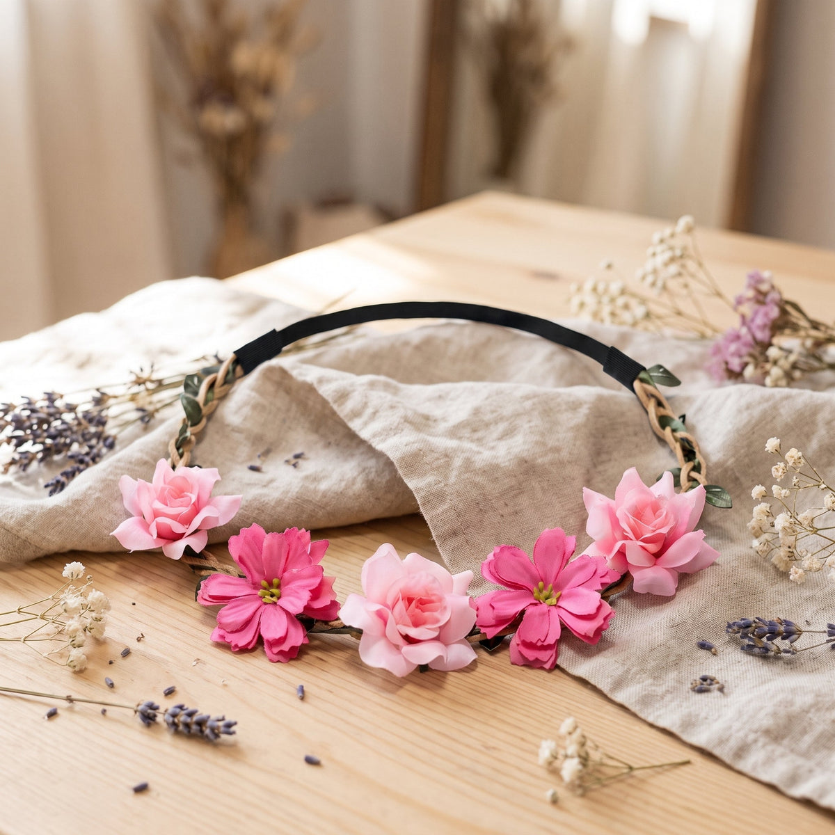 Pink fabric flower crown on a wooden table with dried flowers
