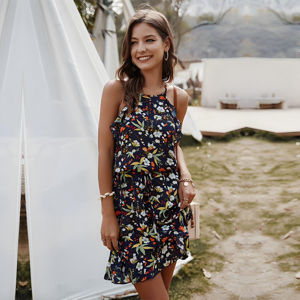 Lachend model draagt de marineblauwe boho jurk met bloemen en halterhals