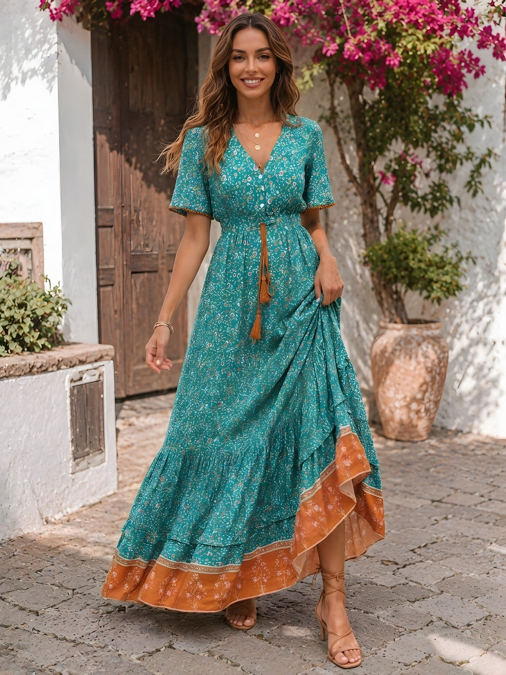 Smiling model wearing the long turquoise floral hippie dress on cobbles
