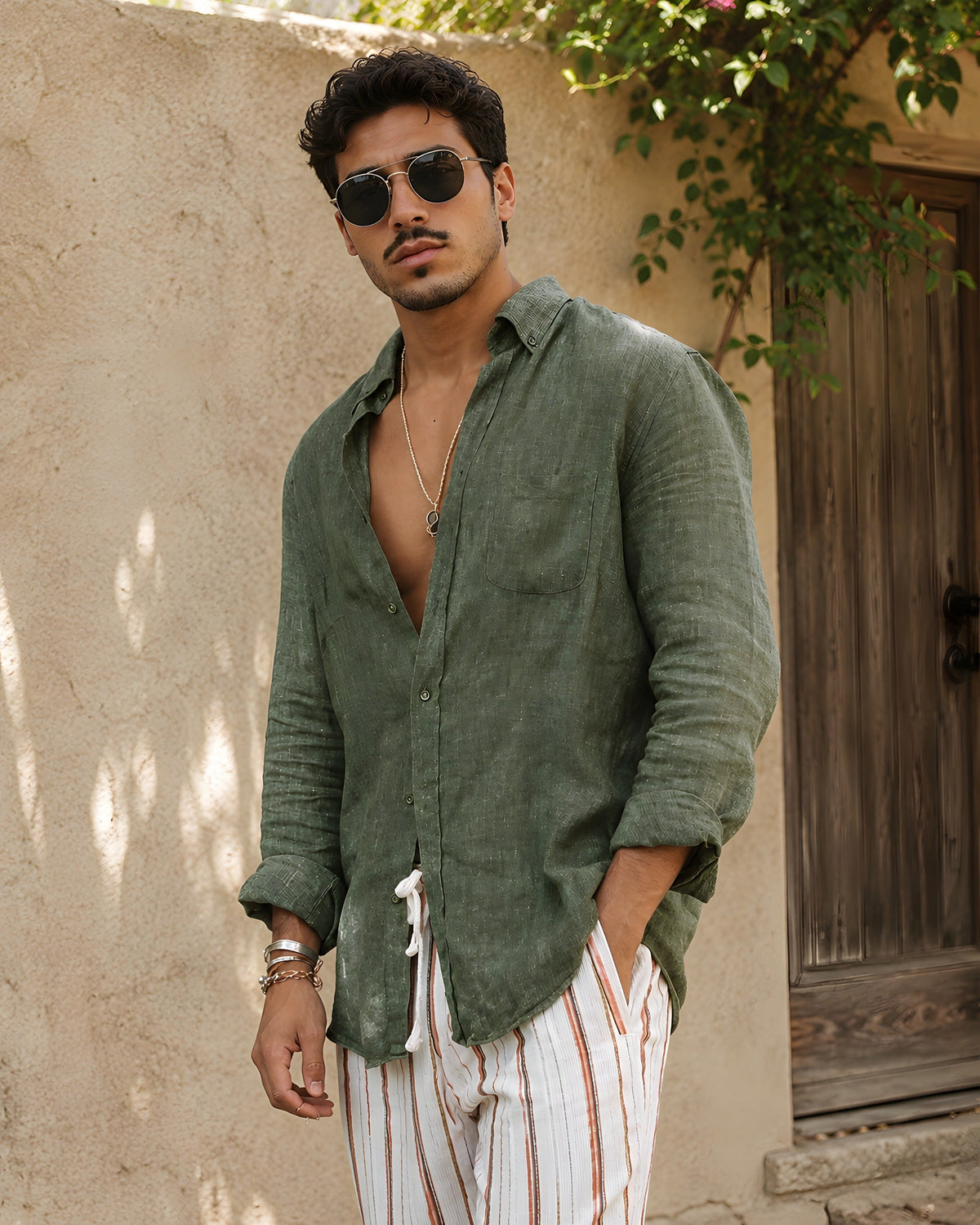 Man wearing the open khaki linen shirt against a stone wall