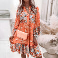 Koralfarvet boho kjole med flæser set forfra med en clutch
