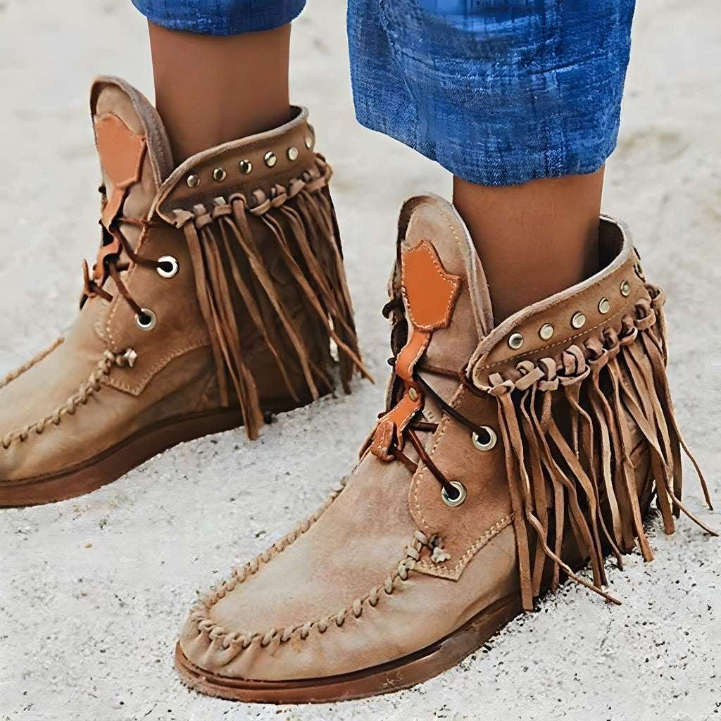 Camelkleurige laarzen met franjes bij opgerolde blauwe jeans, close-up