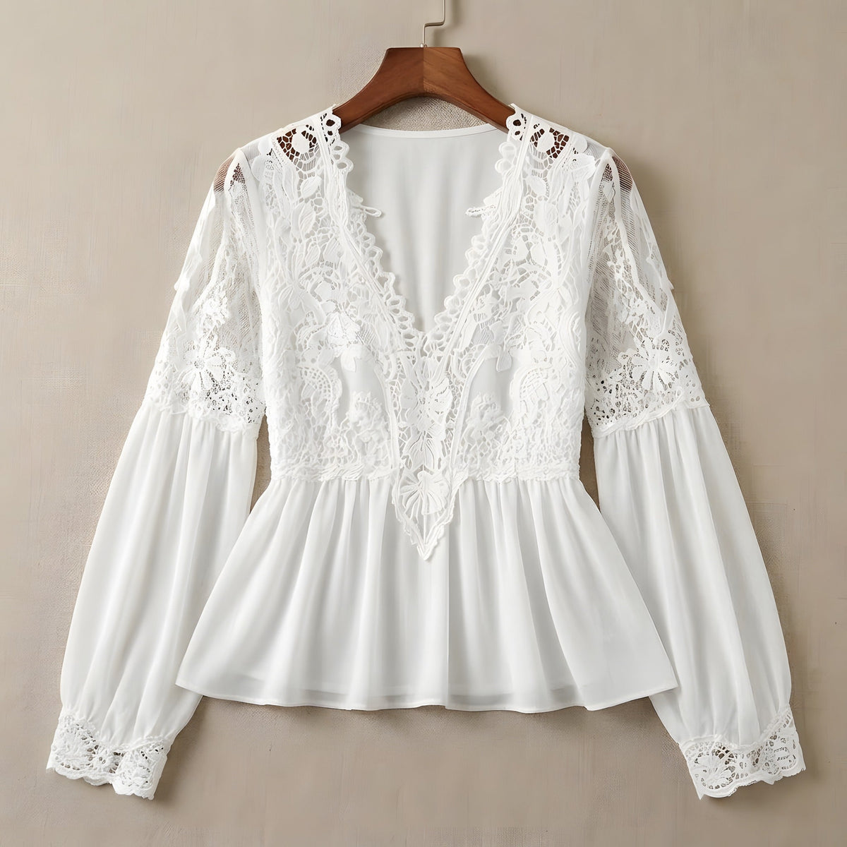 White guipure lace blouse with puff sleeves on a wooden hanger