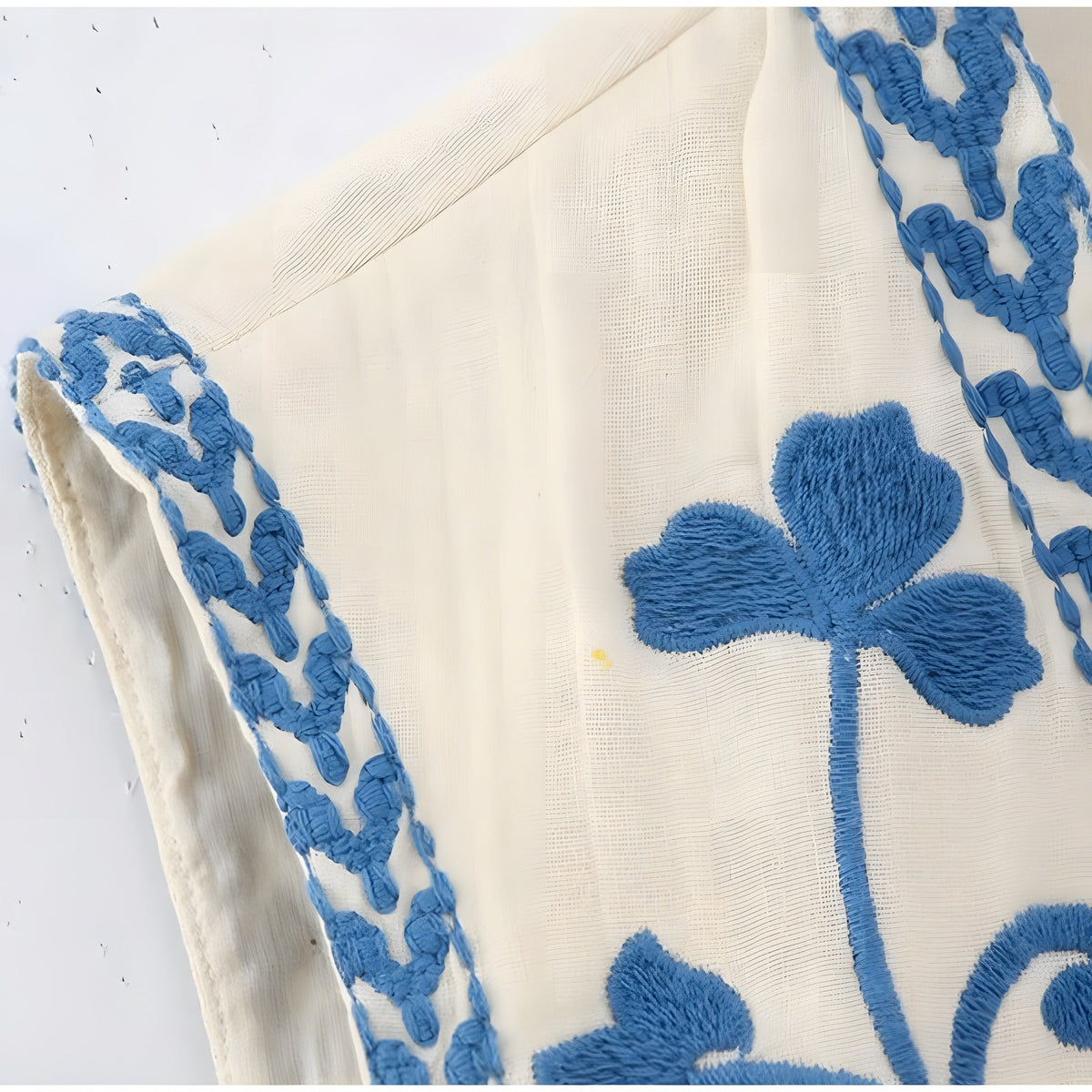 Close-up of the blue floral embroidery on the sleeveless vest