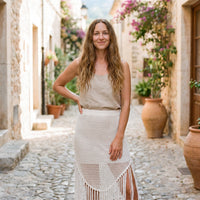 Smiling model wearing the white crochet swimsuit cover up skirt in a Mediterranean alley