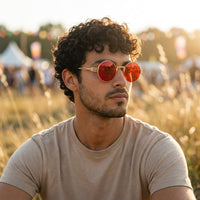 Mann mit runder Hippie Sonnenbrille mit roten Gläsern auf einem Festival