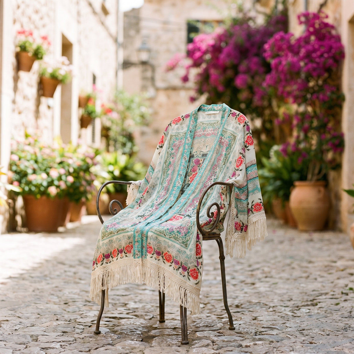 Floral fringed kimono vest draped on a chair in a Mediterranean alley