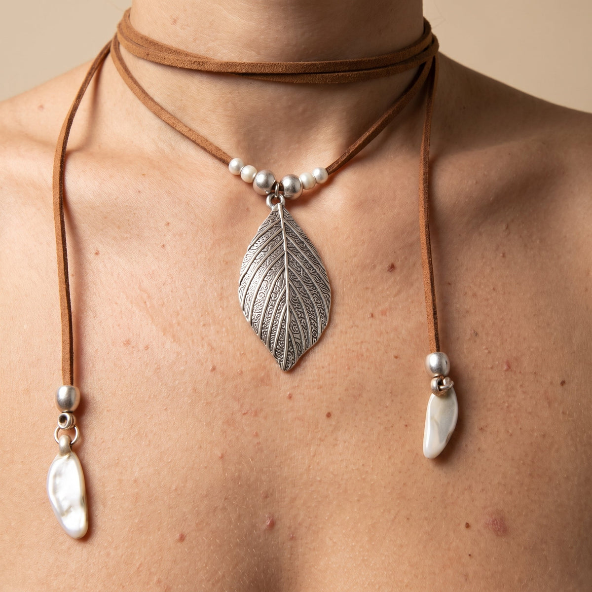 Engraved silver leaf pendant worn on a suede cord