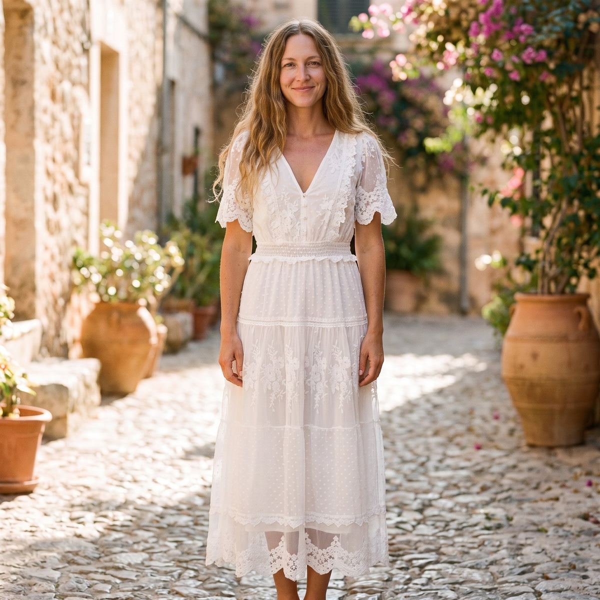 White ruffled boho maxi dress worn by a smiling model, Mediterranean alley