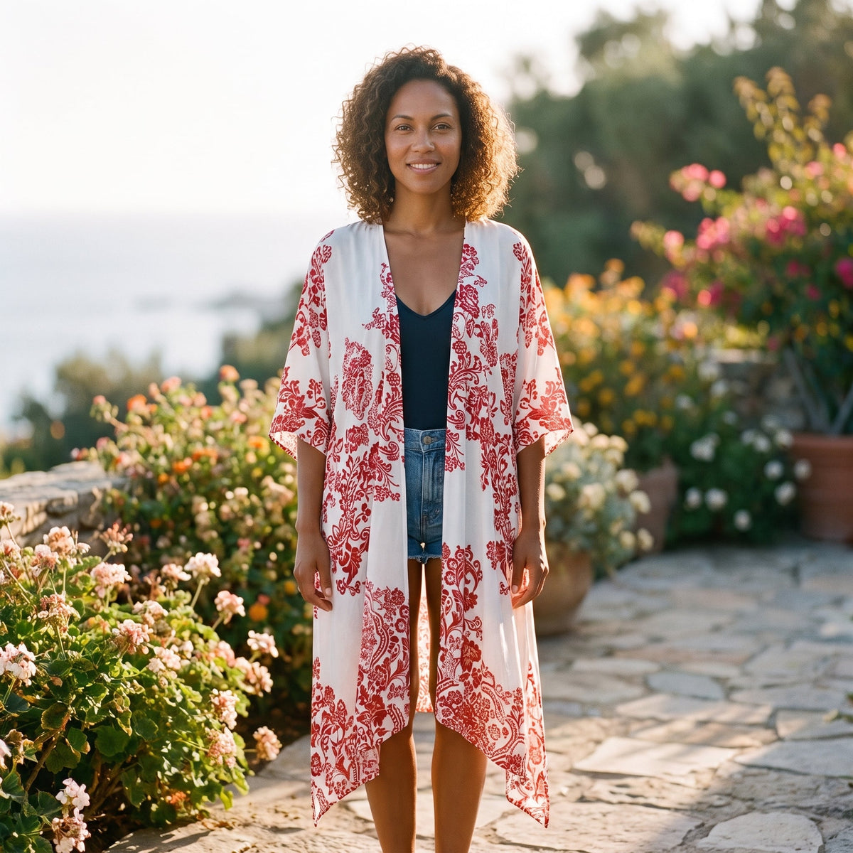 Red porcelain print beach kimono worn by a smiling model seaside