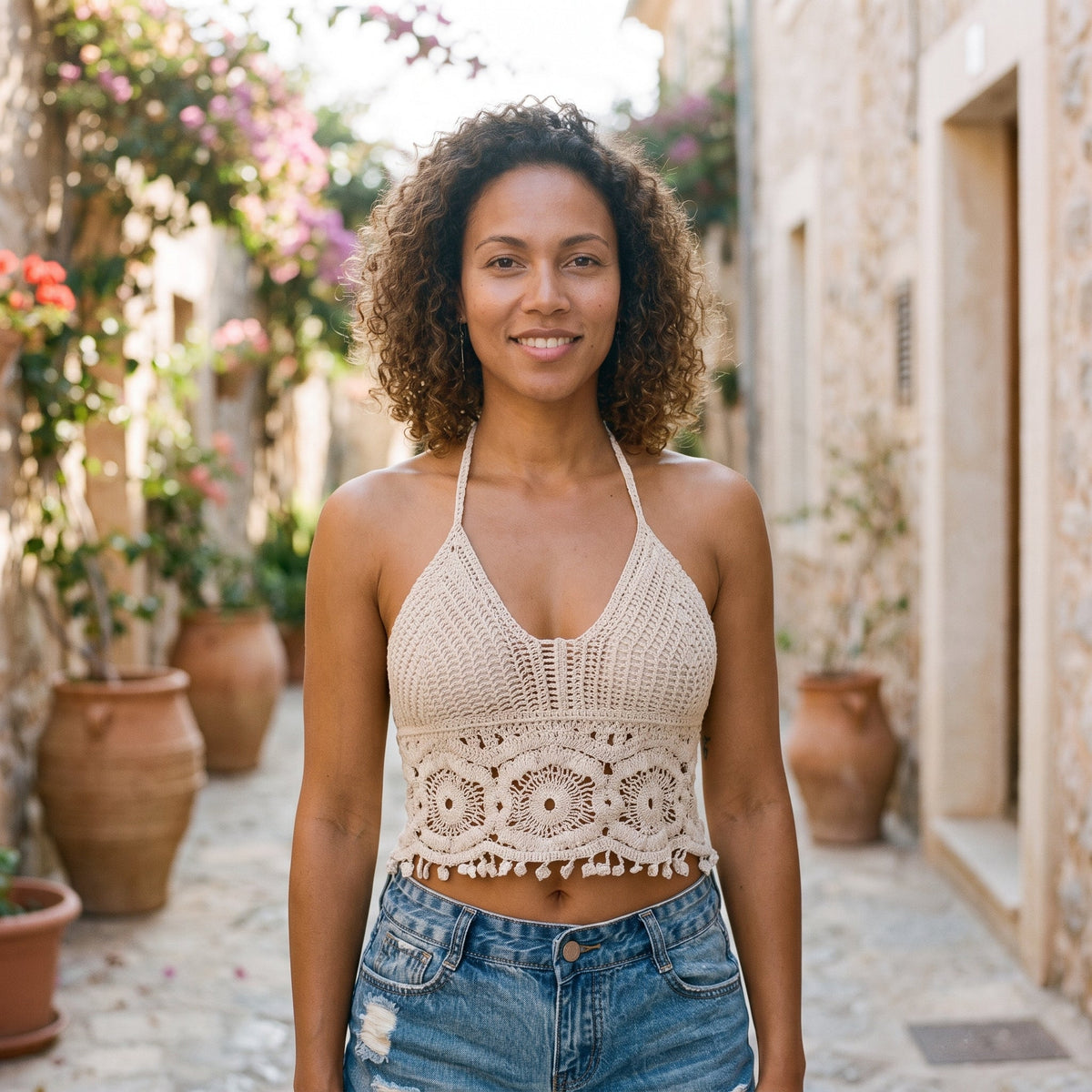 Ivory crochet crop top worn by a smiling model in a sunny alley