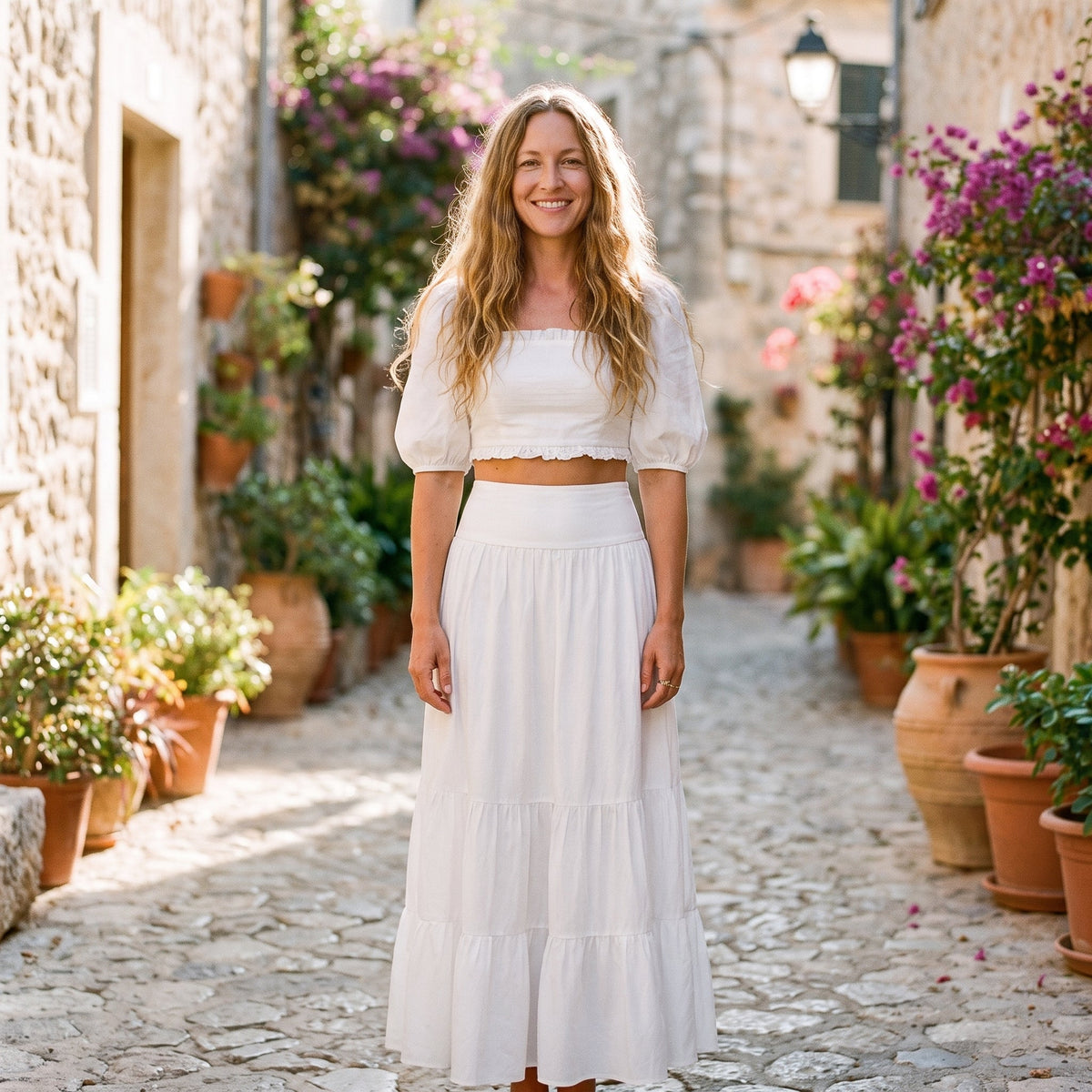 Lang hvid boho flæsenederdel båret af en smilende model i en gyde