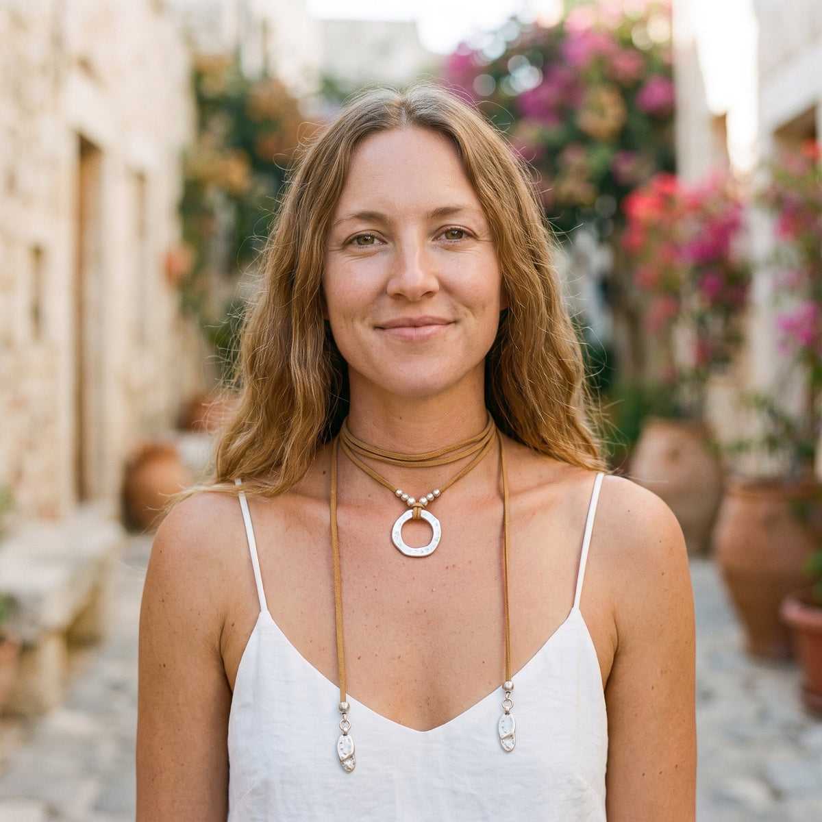 Smiling model wearing the hammered ring hippie necklace in an alley