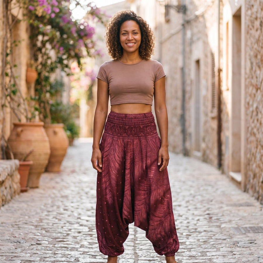 Smiling model wearing burgundy harem pants with peacock feather print