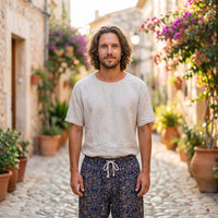 Smiling model wearing gold patterned men's hippie pants in an alley