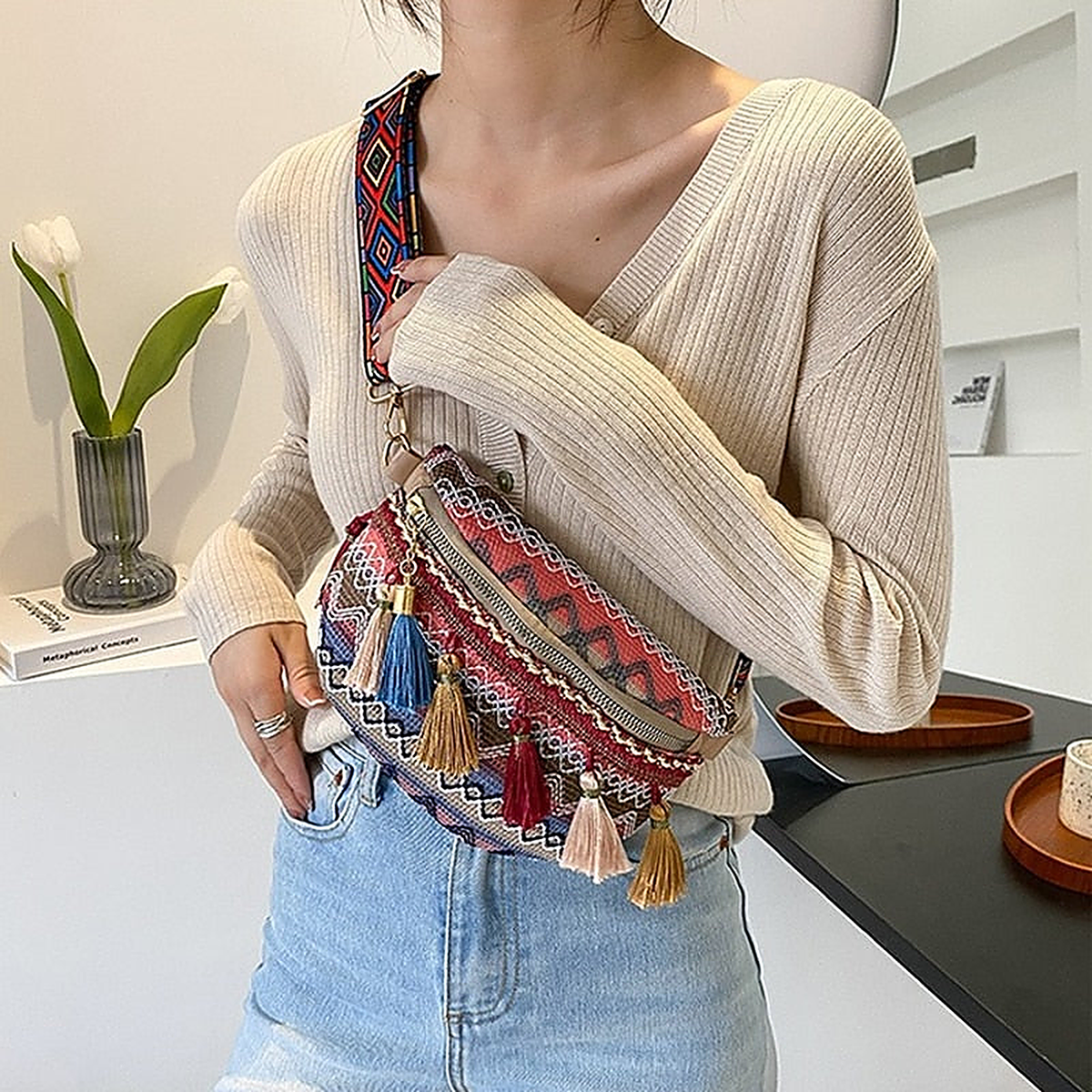 Red fanny pack worn crossbody with Aztec zigzag pattern and pom-poms