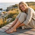 Mujer sonriente con sandalias hippies de cuentas junto al mar