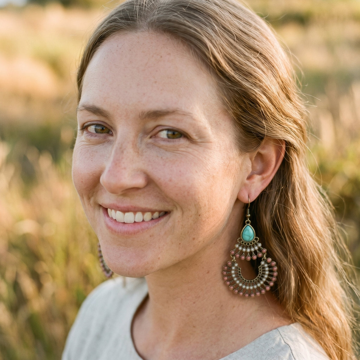 Smiling boho woman wearing turquoise drop hippie earrings