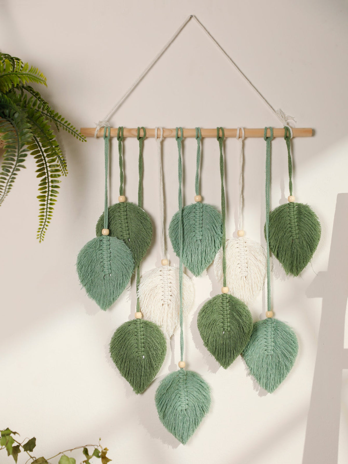 Sage green cotton macrame wall hanging with leaves on wooden branch