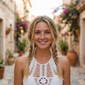Lächelndes Model im weißen durchbrochenen Häkel-Crop-Top, mediterrane Gasse