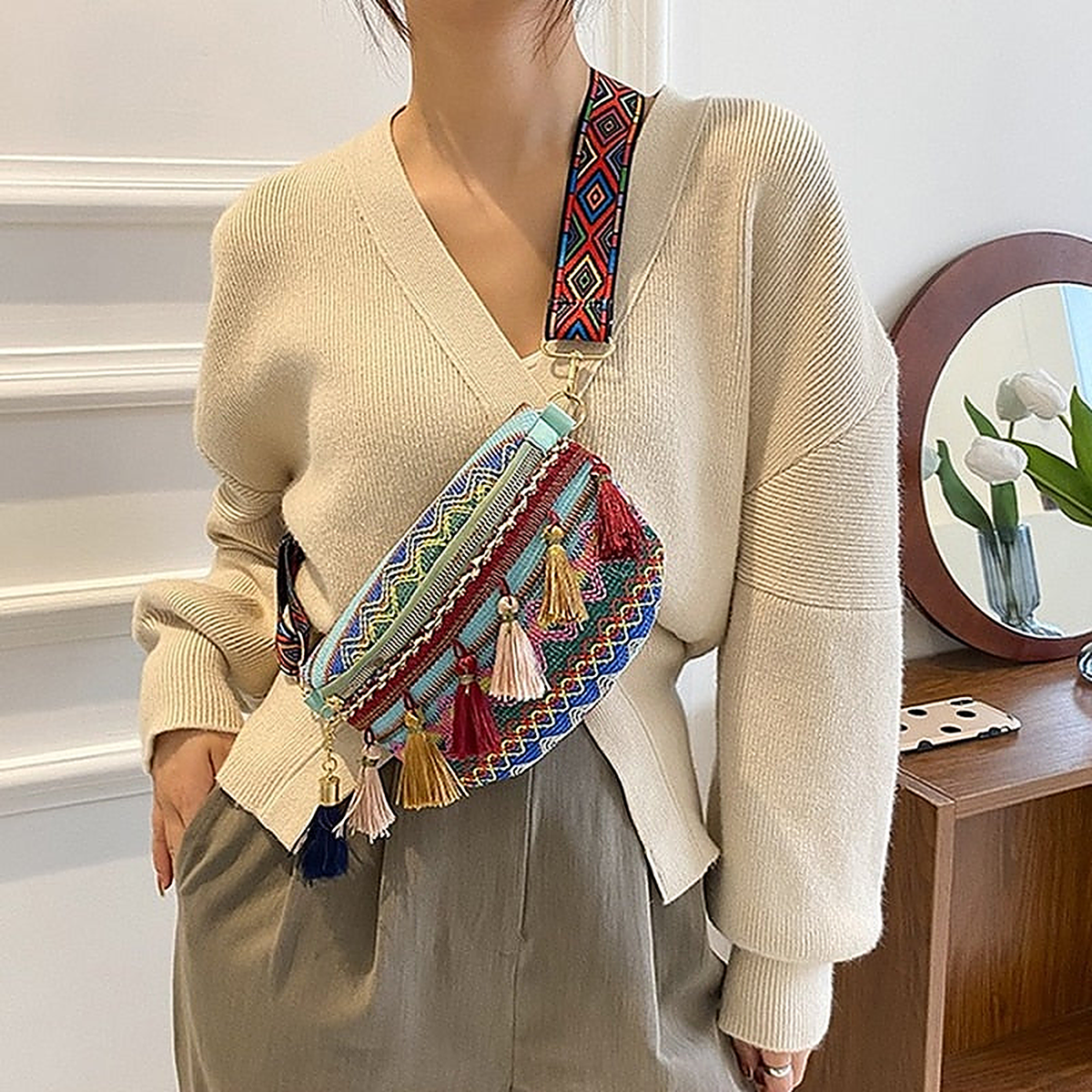 Green hippie belt bag worn across the body, woven border and pom-poms